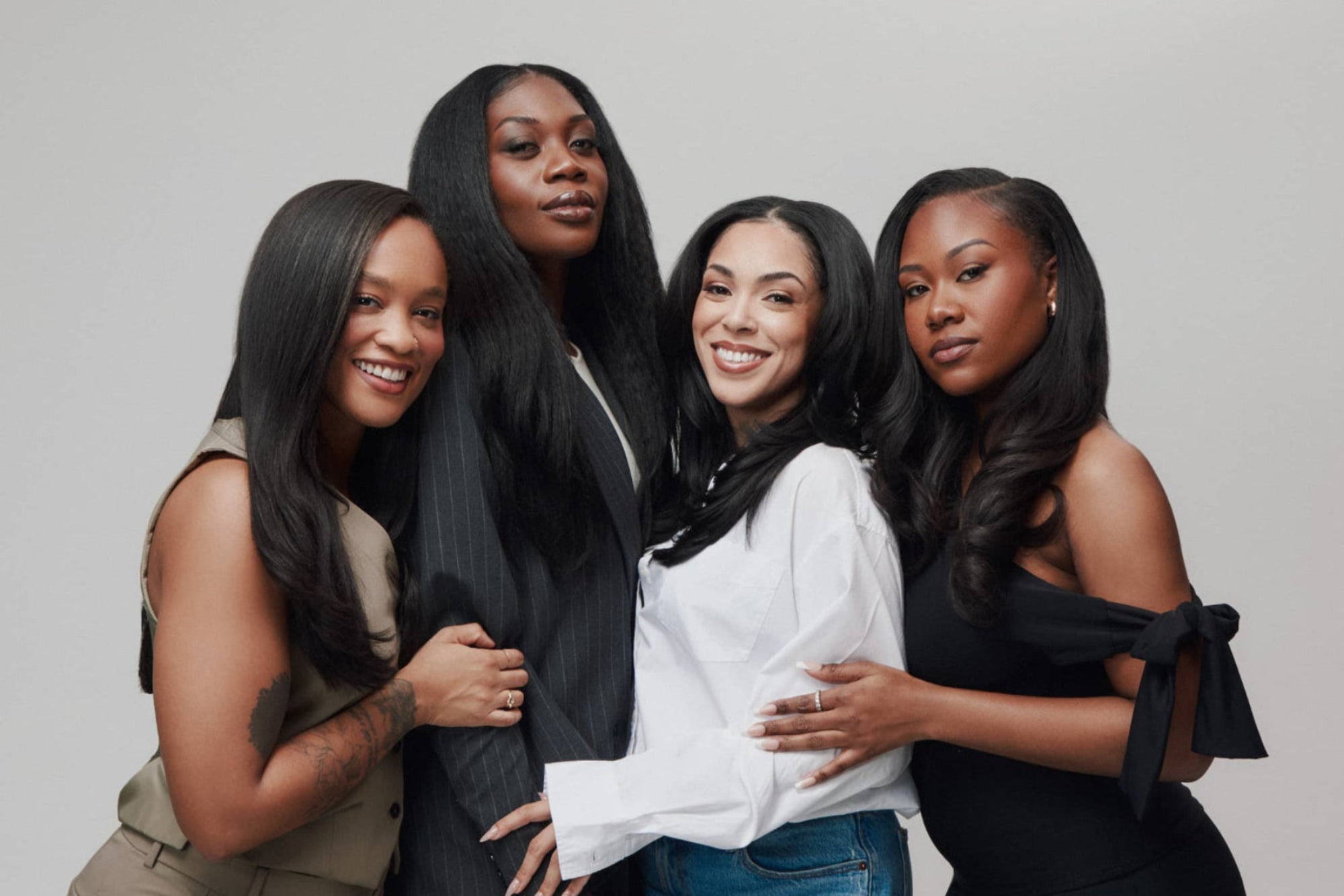 Four women with long, styled hair posing together against a neutral background