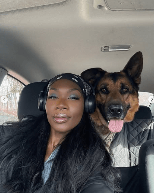 Woman wearing headphones sitting in a car with a German Shepherd dog.